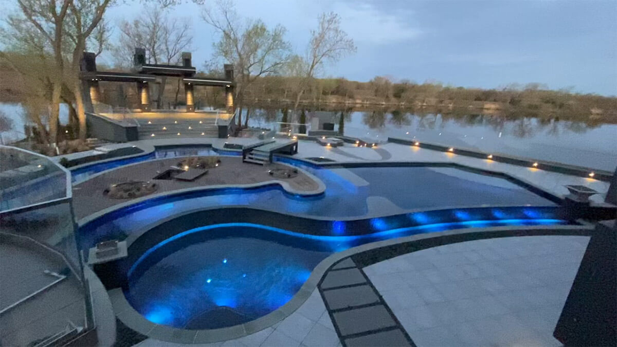 Backyard pool with lazy river and blue LED lighting.
