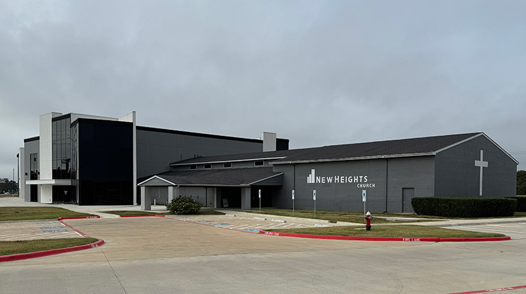 Exterior view of the front of New Heights Church. It's a gray building with many different finishes.