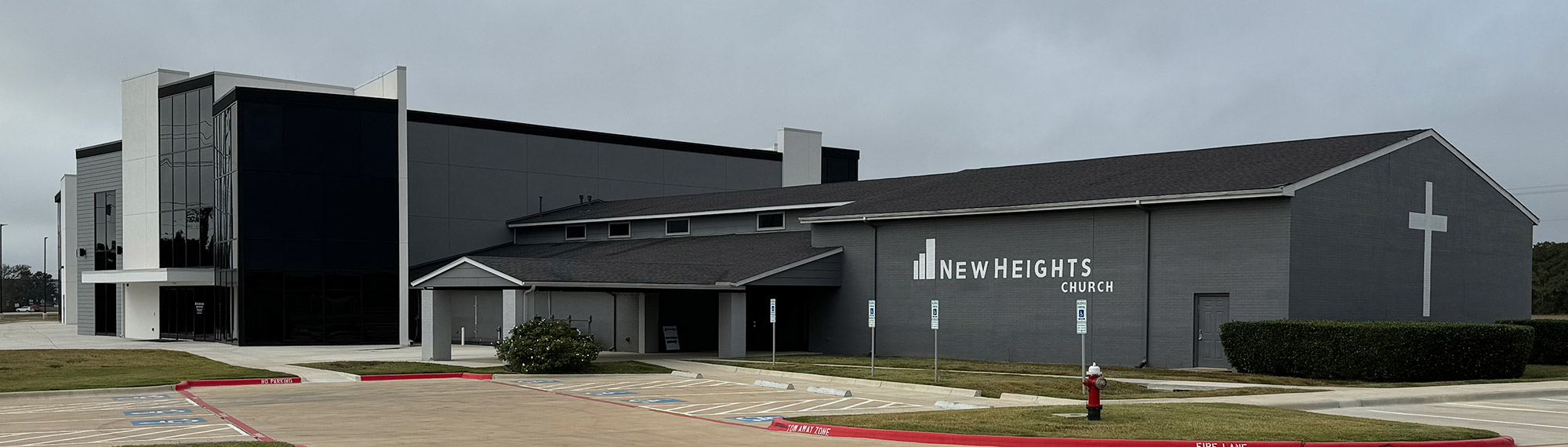Exterior view of the front of New Heights Church. It's a gray building with many different finishes.