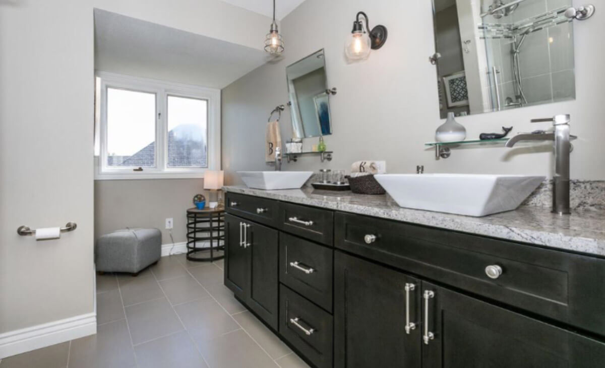 Bathroom double vanity with black cabinets, gray countertops and white sinks.