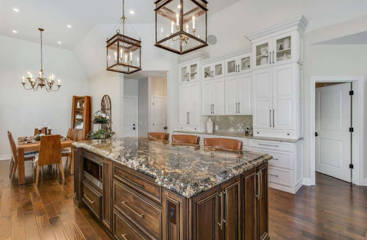 Luxury kitchen with granite countertops and white cabinets. The island is stained wood.